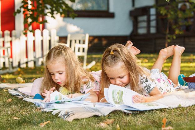 cute-little-blond-girls-reading-book-outside-grass_155003-5149